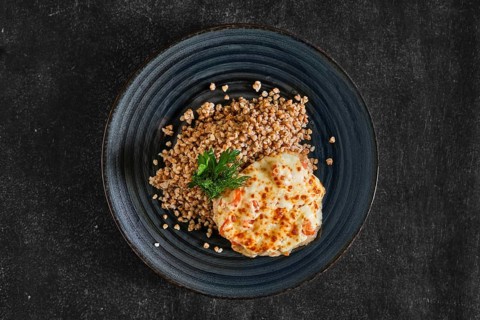 Top view of chopped pork meat baked with cheese and tomato served with buckwheat porridge