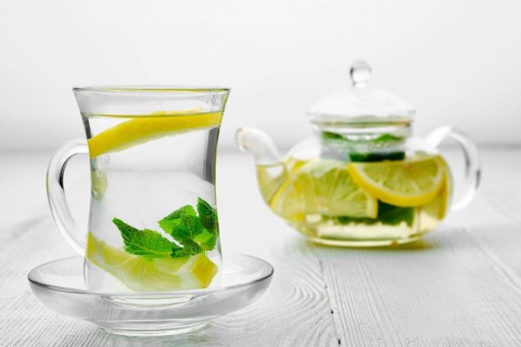 Antioxidant hot drink with lemon and mint in transparent tea pot and glass