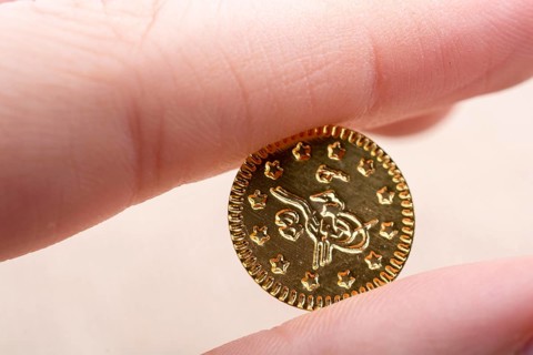 Fake gold coins in hand between fingers on canvas
