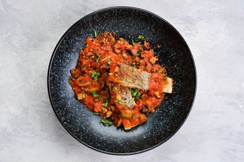 Top view of roasted zander served with steamed tomato