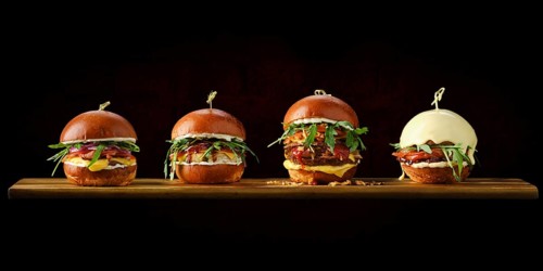 Set of four burgers with different types of meat on wooden serving board