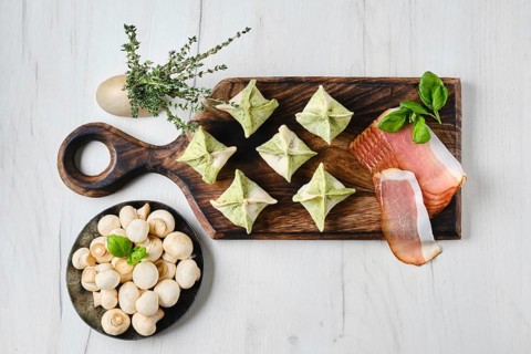 Top view of dumplings stuffed with smoked ham and mushrooms on wooden serving board