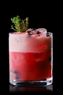 Variation of whiskey sour cocktail with black currant syrup isolated on black background