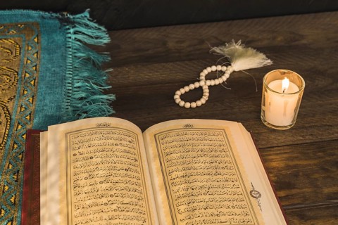 Prayer beads candle near religious book