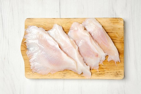 Overhead view of raw fresh peeled stingray wings on wooden cutting board