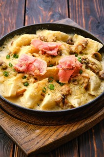 Close up view of pan with fried meat dumplings with bacon and mushroom sauce