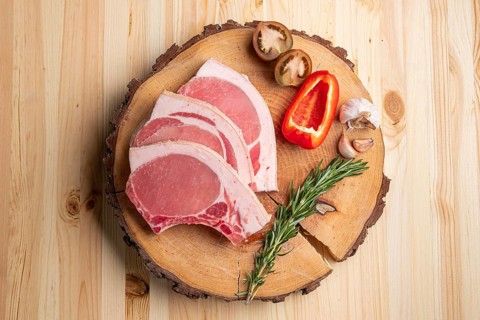 Raw fresh pork fillet steak on the bone on wooden cutting board