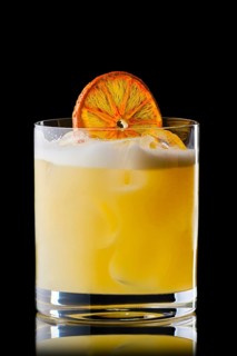 Variation of whiskey sour cocktail with orange syrup isolated on black background