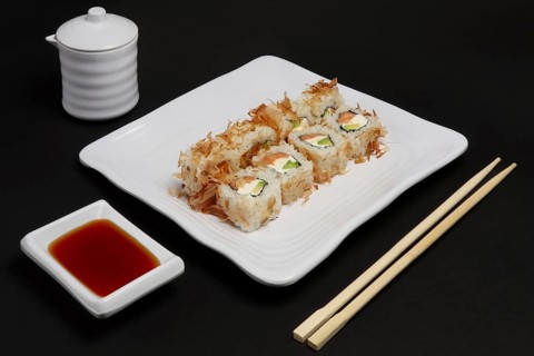 Portion of bonito rolls served on plate with soy sauce and wooden hashi