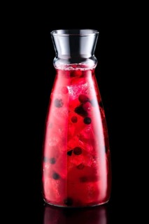 Cold sangria with forrest berries in a jar isolated on black background