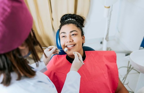 Close up of female dentist doing dental checkup to smiling patient