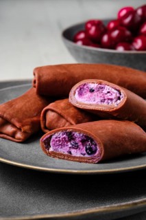 Closeup view of thin chocolate pancakes stuffed with curd