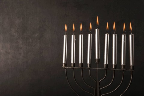 Menorah with candles near gray wall