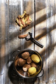 Top view of fresh potatoes and potato peelings with a knife on a table