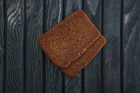 Two pieces of brown bread on dark wooden table. Top view