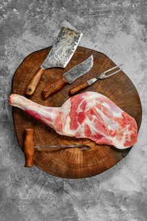 Top view of raw fresh lamb shoulder chump on butcher's cutting log