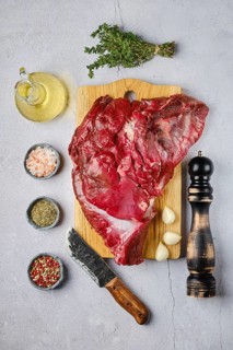 Overhead view of raw fresh deer boneless ham with spice and herb over concrete background