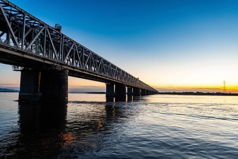 Giant bridge spanning over the Amur river at sunset