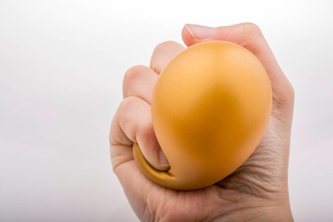 Squeezing yellow balloon with hand on a white background