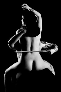 Man strokes woman's naked back with violin bow
