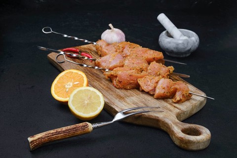 Skewers with raw turkey meat with sweet and spicy rub on dark background
