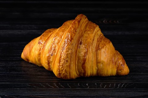 Fresh golden croissant on black table