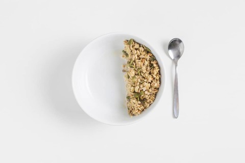 Granola with pumpkin seeds white bowl spoon white background