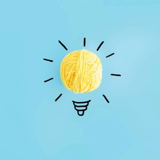 Light bulb made with yellow ball yarn blue backdrop