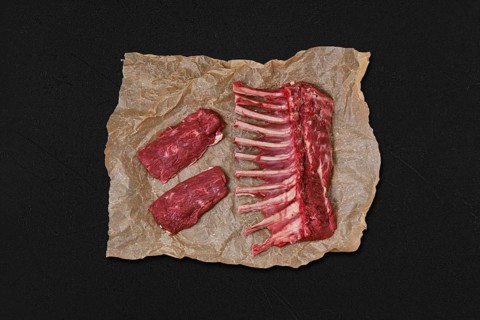 Overhead view of raw fresh rack of lamb and steak in wrapping paper