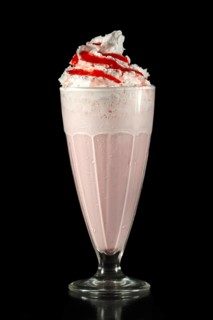 Milkshake cherry summer cocktail in tall facetted glass isolated on black