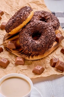 Overhead view of chocolate donuts on bright wooden background