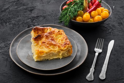 Cheese puff pie from unleavened dough on black wooden background