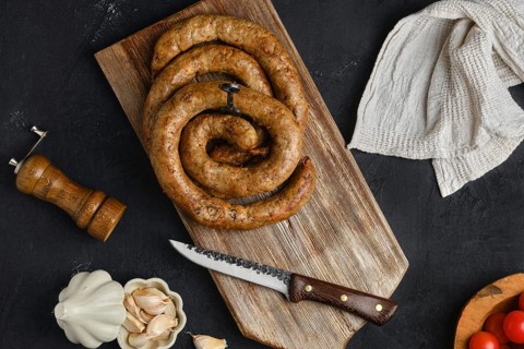 Horse meat sausage with garlic rolled on wooden cutting board