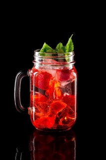 Cold fruit lemonade in mason jar isolated on black background