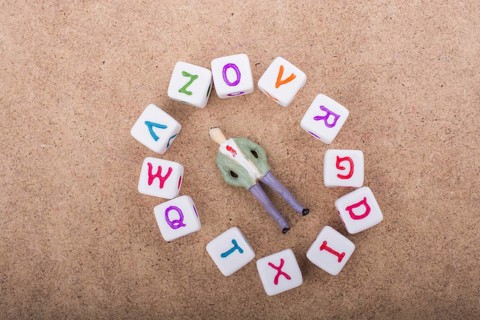 Figurine resting in the middle of the circle formed by alphabet letter cubes