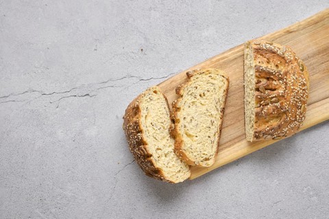 Fresh oats bread with sunflower seeds and sesame on wooden table