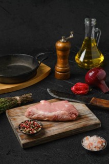 Raw veal steak bone in with ingredients for cooking on black background