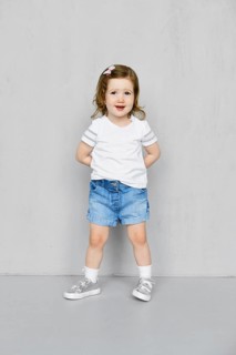 Two years old girl in white t-short and jeans shorts posing in studio