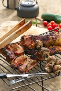 Grilled ribs and champignon on skewer served with fresh cucumber and tomato on wooden table outdoor