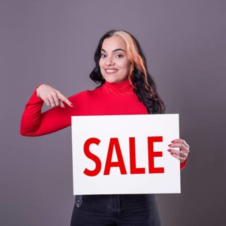 Beautiful woman pointing at a Sale sign. Commercial concept. Commerce
