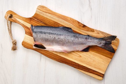 Top view of raw fresh headless pink salmon on wooden cutting board