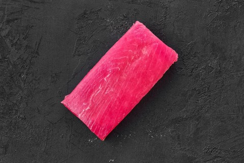 Raw frozen tuna fillet on black background