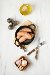 Raw traditional homemade British banger pork sausage ready for frying on wooden table