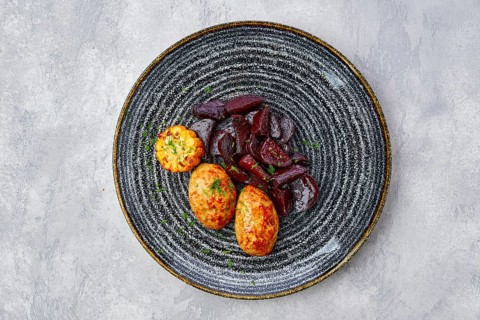 Top view of plate with fried pork cutlet with roasted beetroot slices and grilled maize