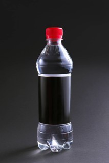 Plastic bottle of water with black label and red cap on table