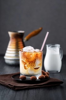 Iced coffee with cream on dark wooden table