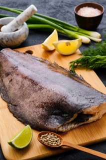 Raw fresh halibut without head on wooden cutting board