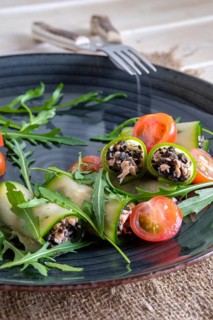 Chopped smoked salmon and black olives rolled in cucumber decorated with tomato and arugula