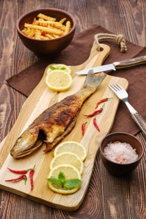 Fried sea bass with fried potato on wooden cutting board