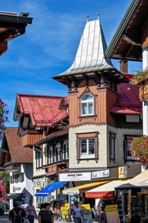 Pedestrian zone with tourists and classic wooden building with wooden shingle facade